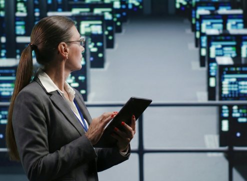 Bild eines Technikers, der eine Serverfarm in einem beleuchteten Rechenzentrum prüft